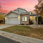 A house with fall landscaping with a pink sunset in the background