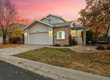 A house with fall landscaping with a pink sunset in the background