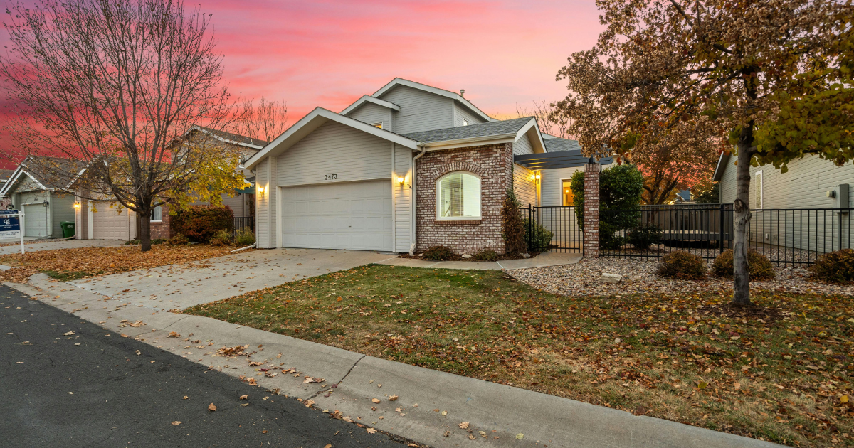 A house with fall landscaping with a pink sunset in the background